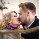 man and woman kissing near green leafed tree