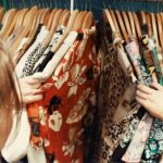 person holding assorted clothes in wooden hanger