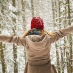 woman wearing hoodie spreading her arm near trees with snows