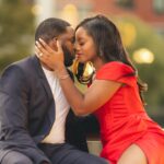 man in black suit kissing woman in red dress