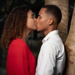 man in white dress shirt kissing woman in red dress