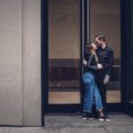 photo of man and woman kissing beside glass doors