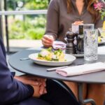 woman in brown cardigan sitting by the table with food