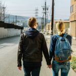 man holding hands of woman walks on concrete road