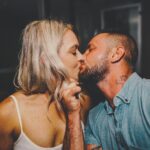 man in blue button up shirt kissing woman in white spaghetti strap top