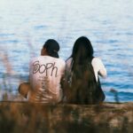 man and woman sitting in front of body of water