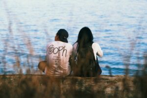 man and woman sitting in front of body of water