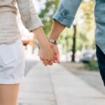 man and woman holding hands together in walkway during daytime