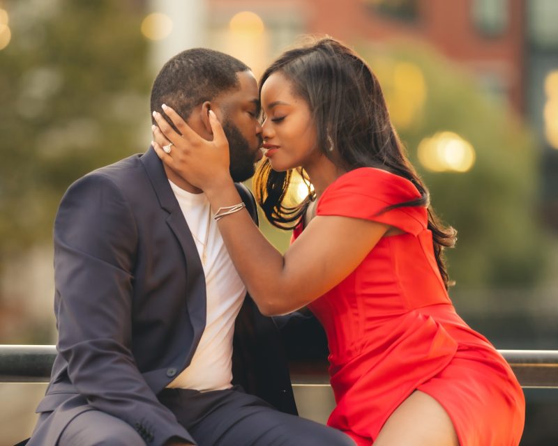 man in black suit kissing woman in red dress