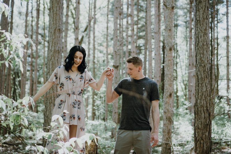 man holding hands with woman near trees